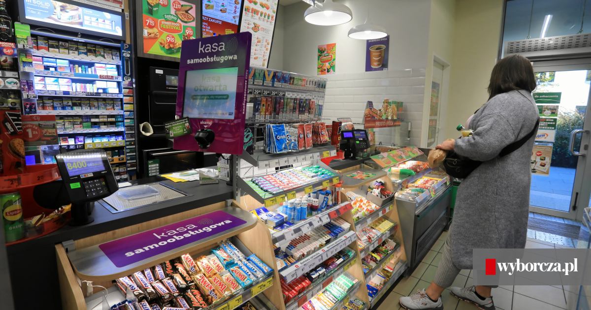Klient w Żabce zaskoczony wysoką ceną paczki papierosów na kasie, jego mina wyraża szok i niedowierzanie.