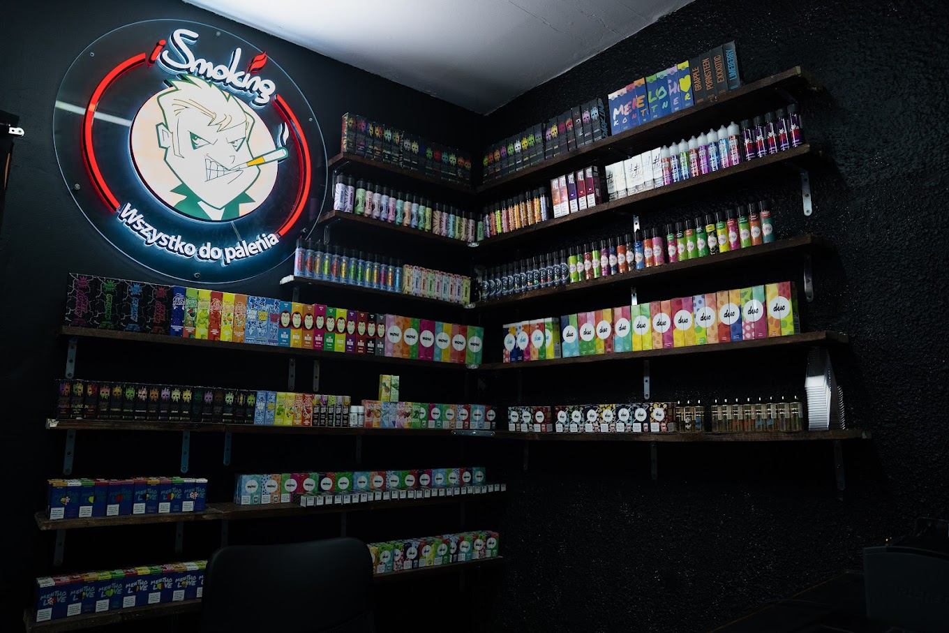Zbliżenie na dłonie osoby nalewającej ciemny liquid o smaku triple berry do kartridża e-papierosa z widoczną grzałką typu mesh.