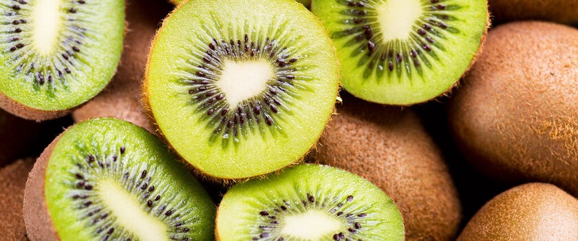 Świeże kiwi i zielone jabłka, symbolicznie przedstawione z elementami wskazującymi na witaminę C i antyoksydanty, np. małe ikony zdrowia lub symbol tarczy.